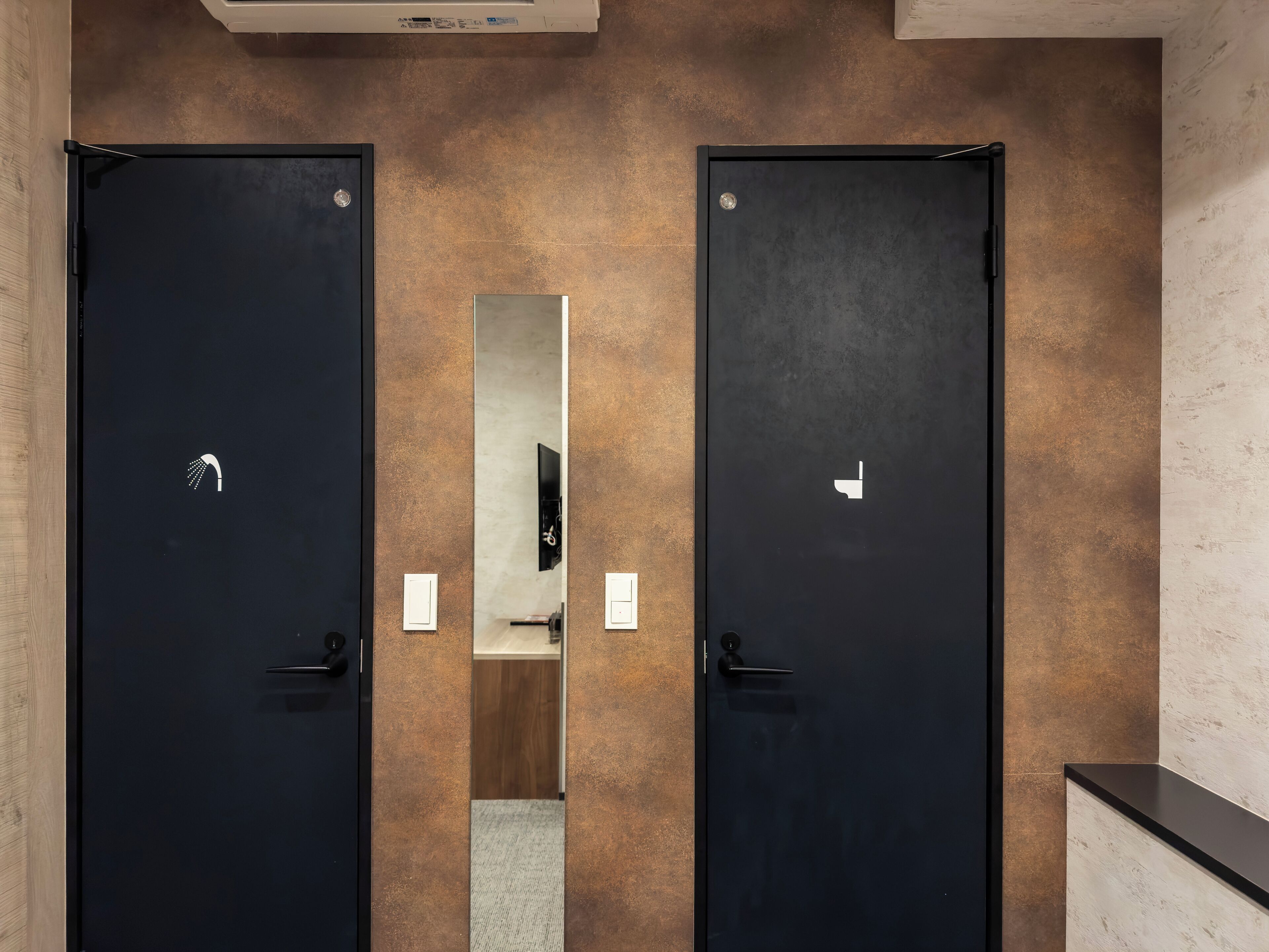Een moderne badkamer met twee zwarte deuren, een spiegel en een handdoekhouder.