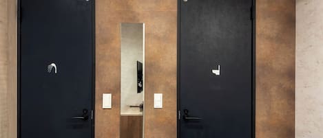 A modern bathroom with two black doors, a mirror, and a towel rack.