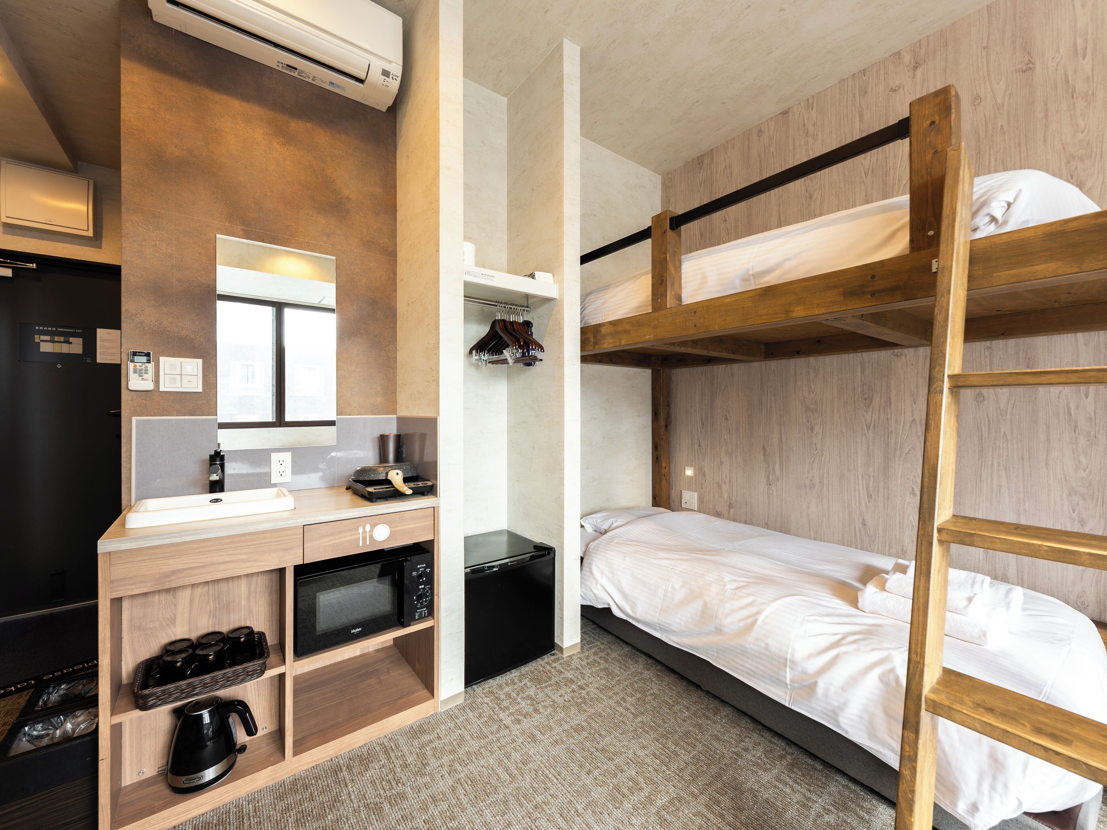 A compact hotel room with a bunk bed, a kitchenette with a microwave, a coffee maker, and a small refrigerator.