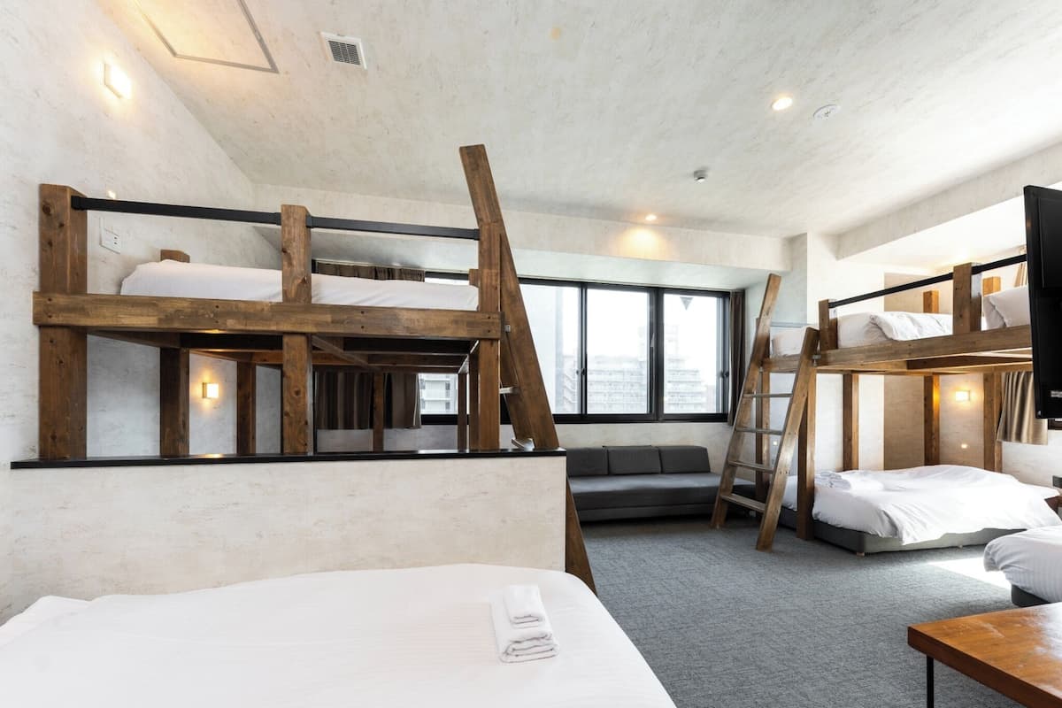 Ein Zimmer mit Etagenbetten, einer Schlafcouch und einem Schreibtisch.