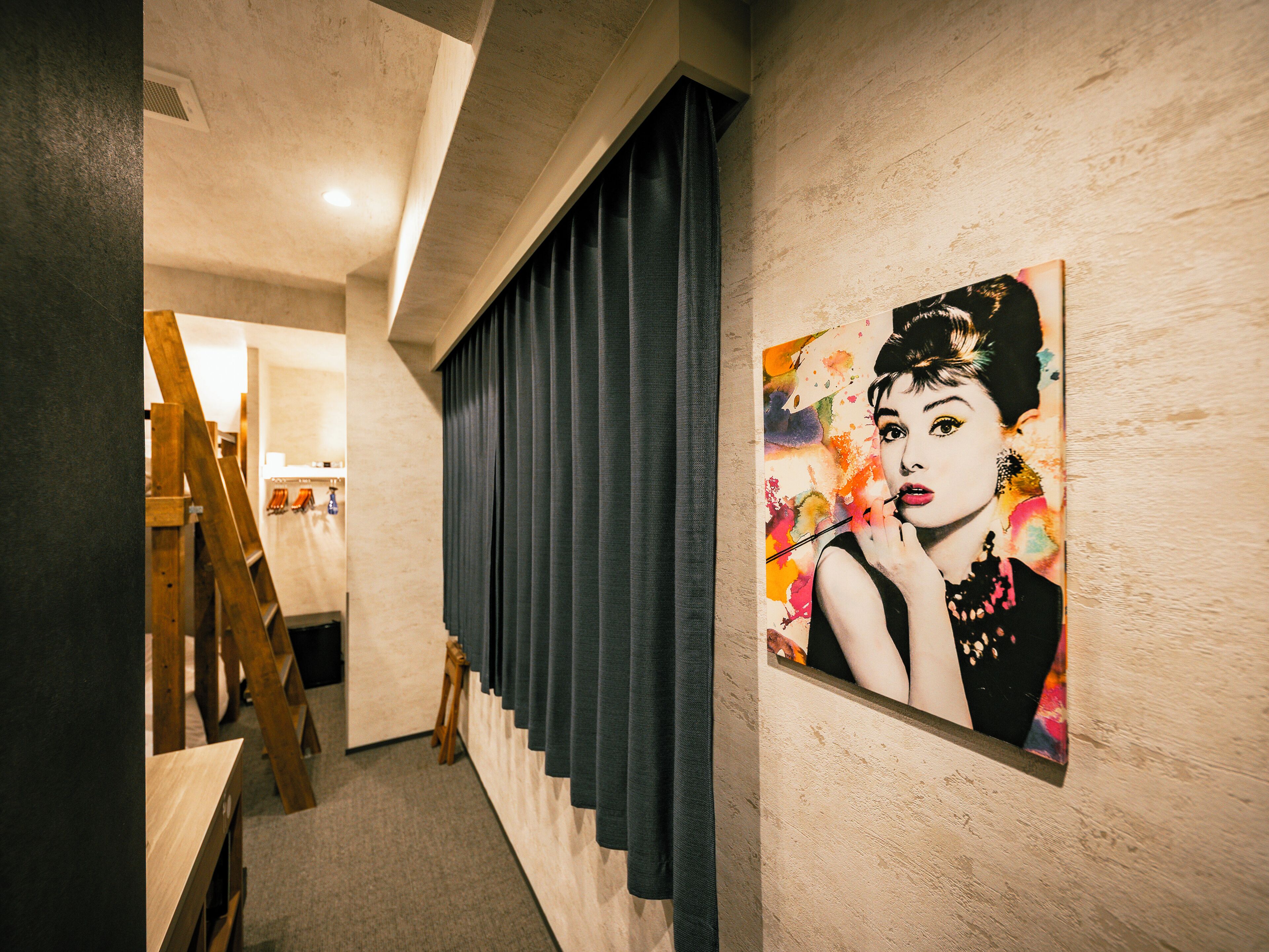 A hallway with a painting on the wall, a wooden easel, and a curtain.