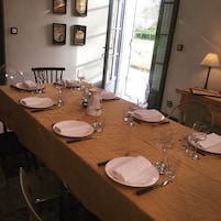 Una mesa de comedor lista para una comida, con platos, cubiertos y copas de vino.