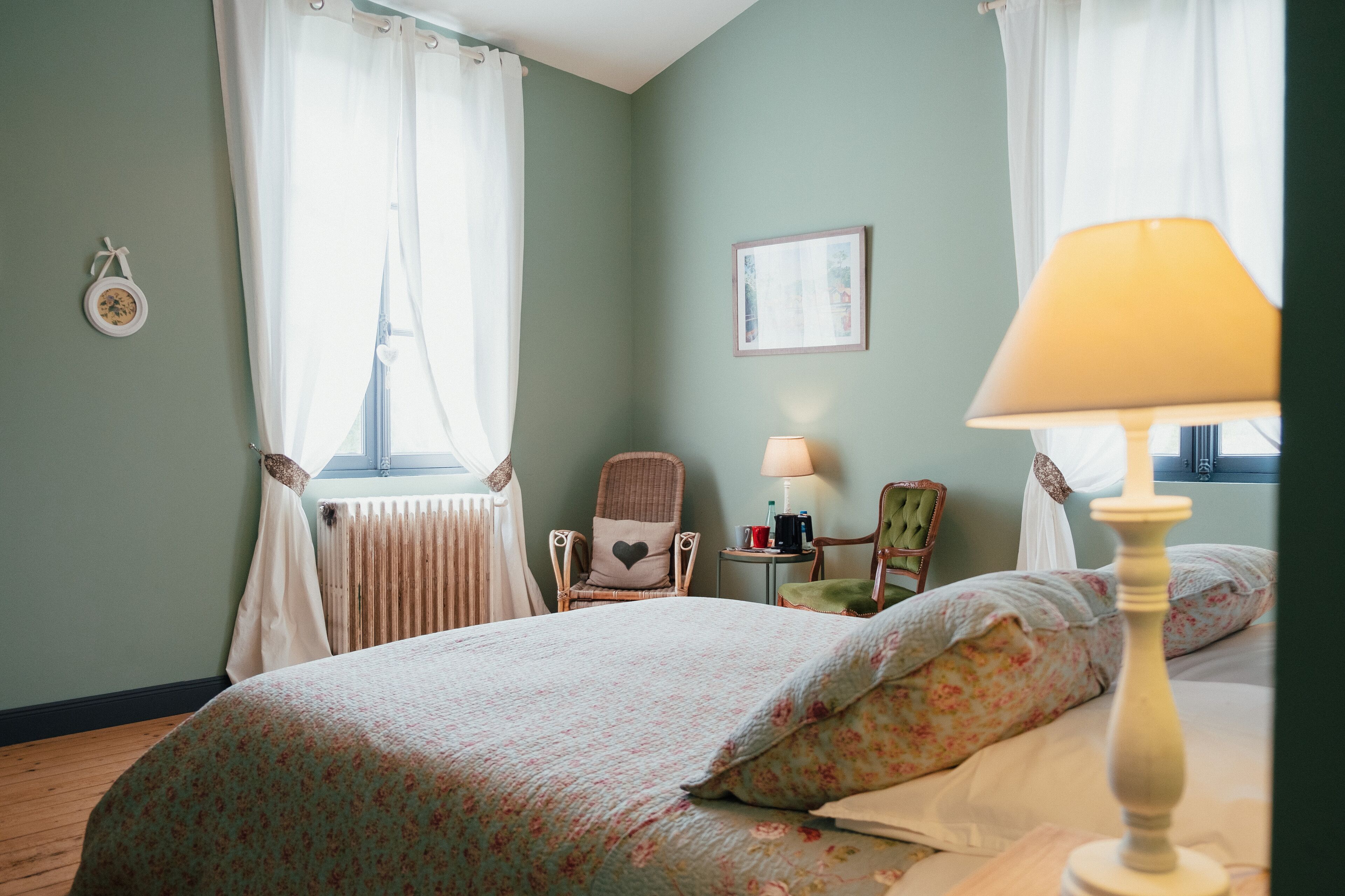 A bedroom with a bed, a chair, a lamp, and a window with curtains.