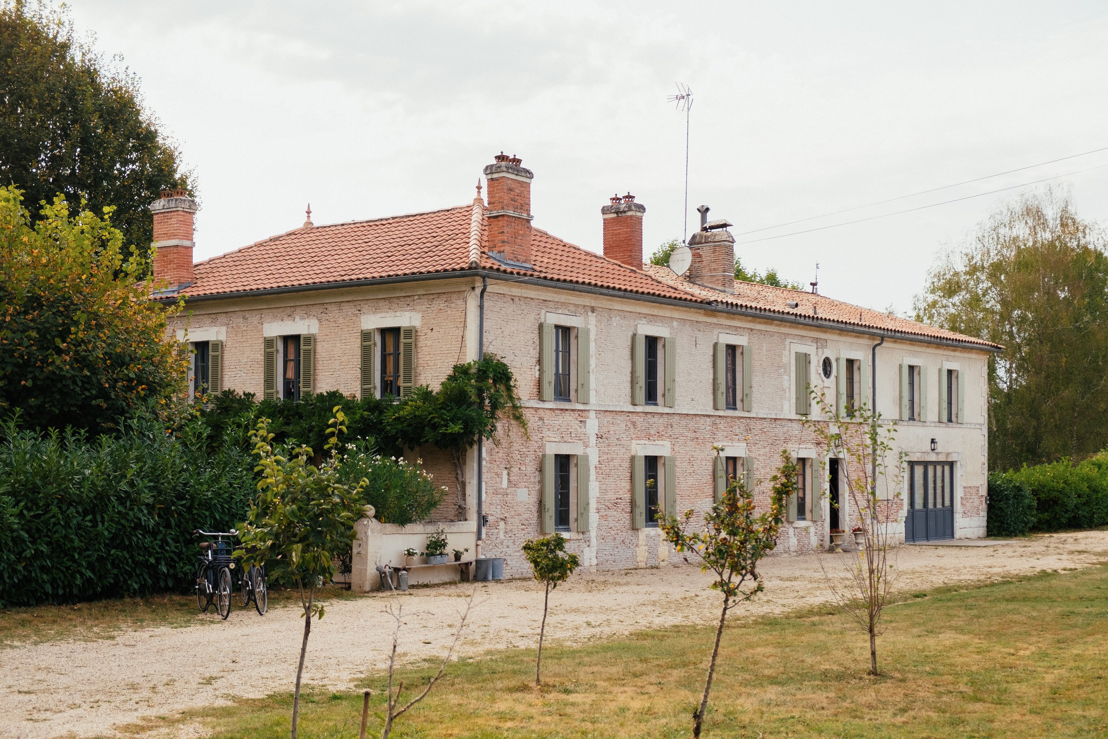 Una casa a due piani con facciata in mattoni, diversi camini e tetto in tegole.