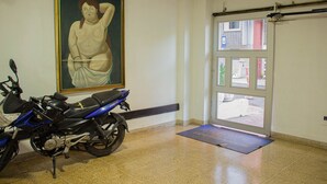 Una habitación con una motocicleta estacionada cerca de una puerta, un felpudo en el suelo y un cuadro en la pared.