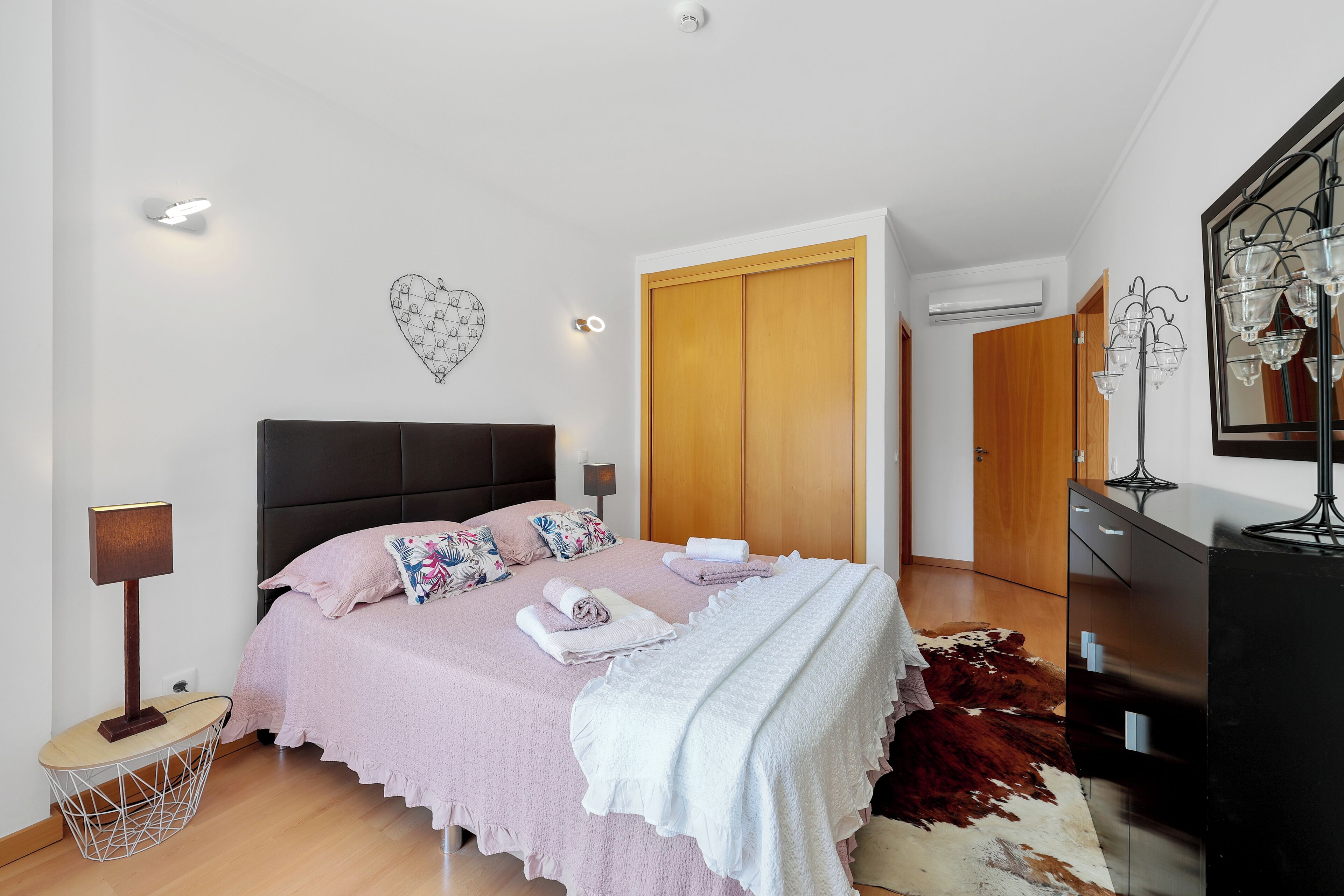 Une chambre à coucher comprenant un lit, des tables de chevet, une armoire et un miroir.