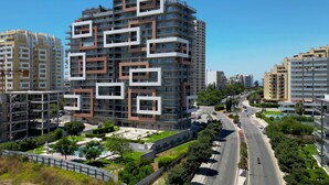 A modern high-rise building with a unique geometric facade, surrounded by a well-maintained urban environment. - T2 standing Praia da Rocha (21052 / AL) (Portimão)
