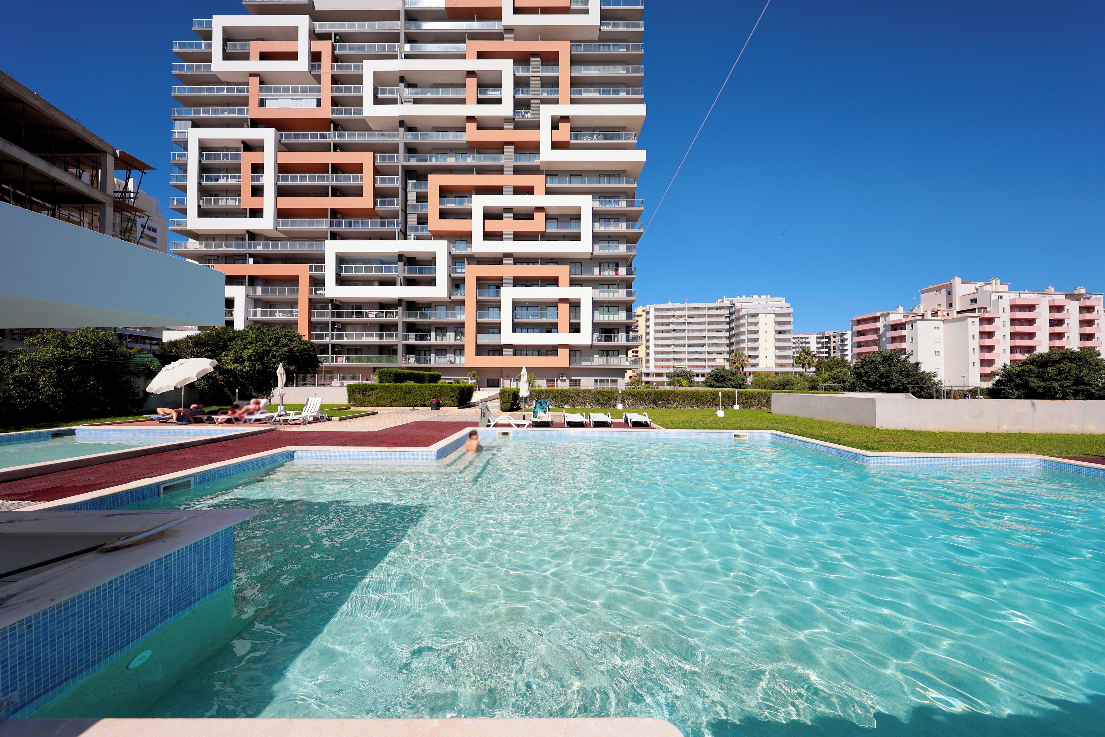 Ein Schwimmbad mit einem modernen Gebäude im Hintergrund.