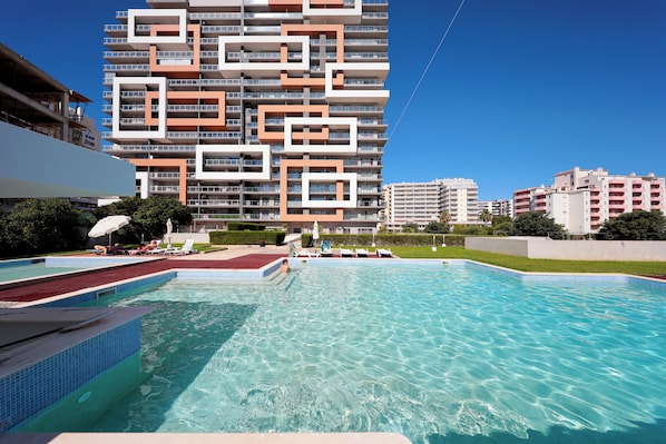 A swimming pool with a modern building in the background. - T2 standing Praia da Rocha (21052 / AL) (Portimão)