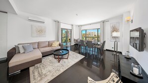 A modern living room with a sofa, coffee table, and dining area with chairs and a table. - T2 standing Praia da Rocha (21052 / AL) (Portimão)