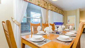 A dining area with a wooden table set for four, white tablecloths, and a blue decorative bowl. - Tigerlilly Private Pool Villa (Davenport)