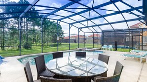 A covered outdoor area with a glass table and chairs, a pool, and lounge chairs. - Tigerlilly Private Pool Villa (Davenport)