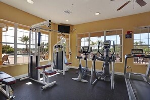 A gym with cardio machines, weight equipment, and large windows offering views of the outdoors. - Casa Viva (Orlando)