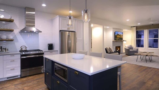 A modern kitchen with a central island, stainless steel appliances, and a dining area with a fireplace. - Casa Blanca (Crested Butte)