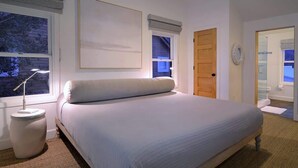 A bedroom with a bed, bedside lamp, window, door, and a mirror. - Casa Blanca (Crested Butte)