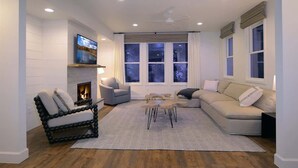 A living room with a fireplace, a sofa, a coffee table, and a TV mounted on the wall. - Casa Blanca (Crested Butte)