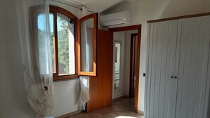 Un dormitorio con cama, armario y baño visible a través de una puerta abierta.