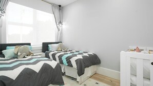 A bedroom with two twin single beds or a double bed with a cot. - A Luxurious Beachfront Getaway  (Blacksmiths)
