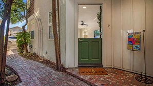 A brick-paved entrance with a green door, a mailbox, and a 'BENCH LIFE' mat. - Indoor/Outdoor Living with Stackable Doors, Firepit, BBQ, Outdoor Heater & More! (Newport Beach)