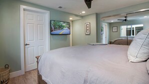 A bedroom with a bed, a ceiling fan, a television, and a door. - Indoor/Outdoor Living with Stackable Doors, Firepit, BBQ, Outdoor Heater & More! (Newport Beach)