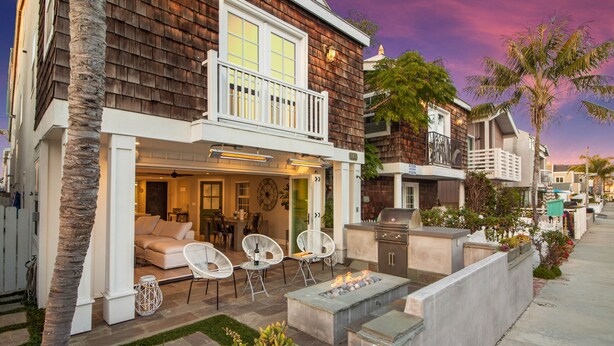 A residential property with a patio, outdoor seating, and a barbecue area. - Indoor/Outdoor Living with Stackable Doors, Firepit, BBQ, Outdoor Heater & More! (Newport Beach)