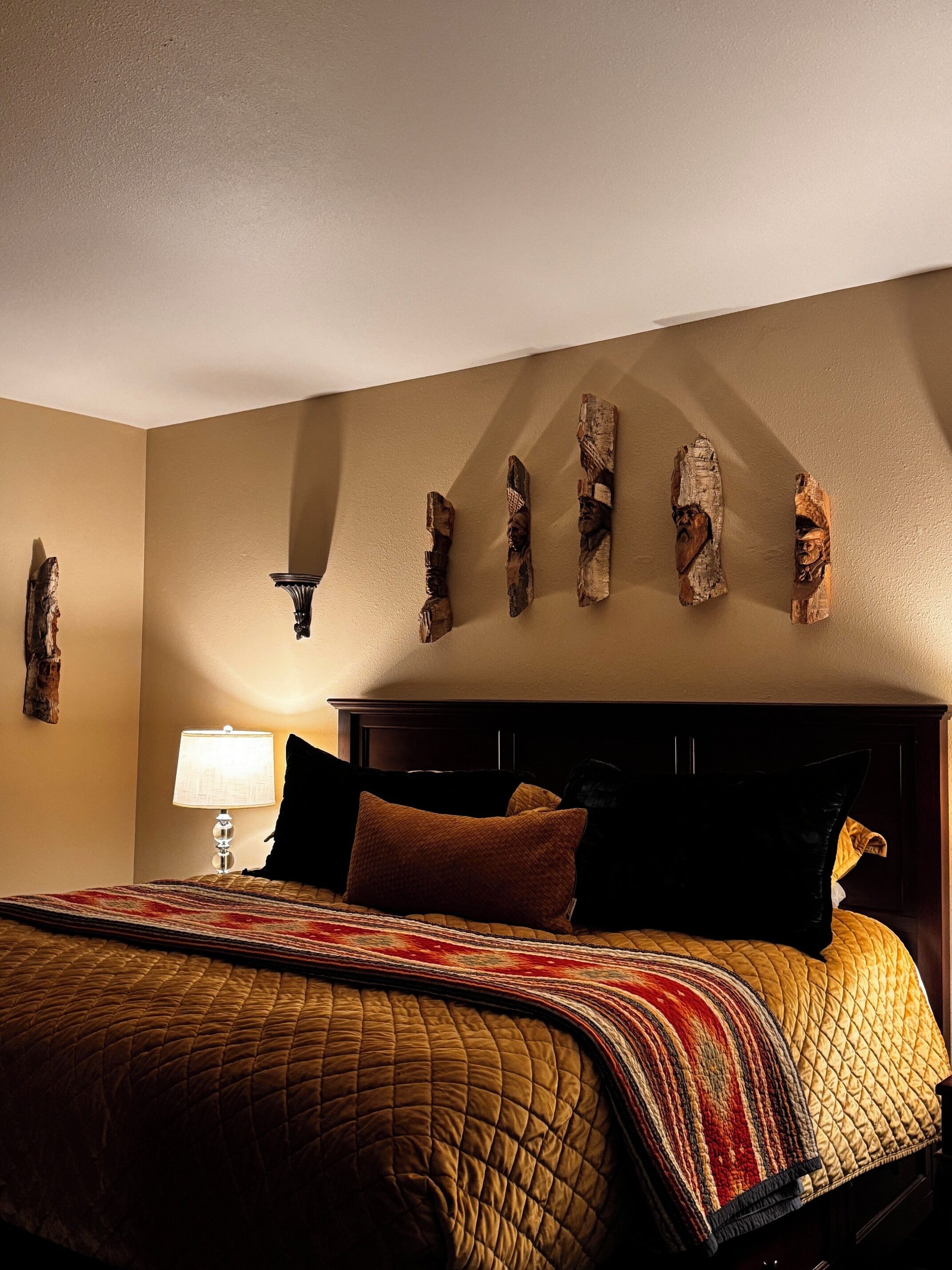 A bedroom with a bed, a nightstand, a lamp, and wall-mounted decor.