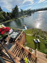 Une terrasse dotée d’un jacuzzi, d’un espace salon extérieur et offrant une vue sur un lac où naviguent des bateaux.
