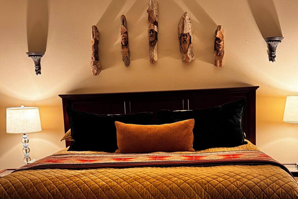 Una cama con cubrecama acolchado, dos lámparas de noche y una lámpara de pared.