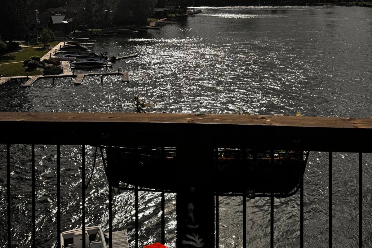 Un río con barcos amarrados a la izquierda, un muelle a la derecha y montañas a lo lejos.