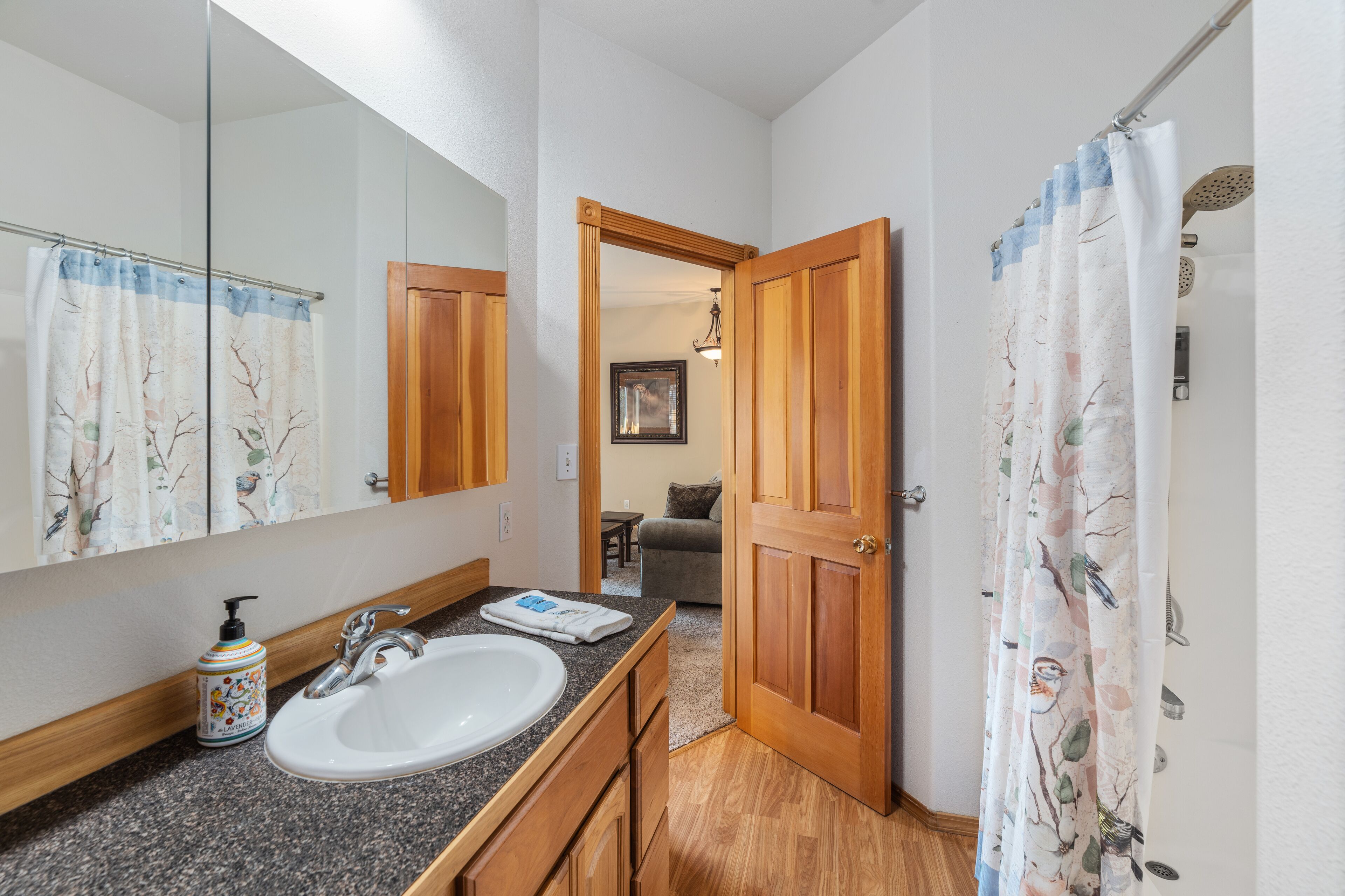 Un baño con lavamanos, espejo y puerta de madera.