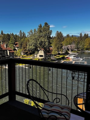 Uma varanda com vista para um lago, barcos atracados e casas ao fundo.