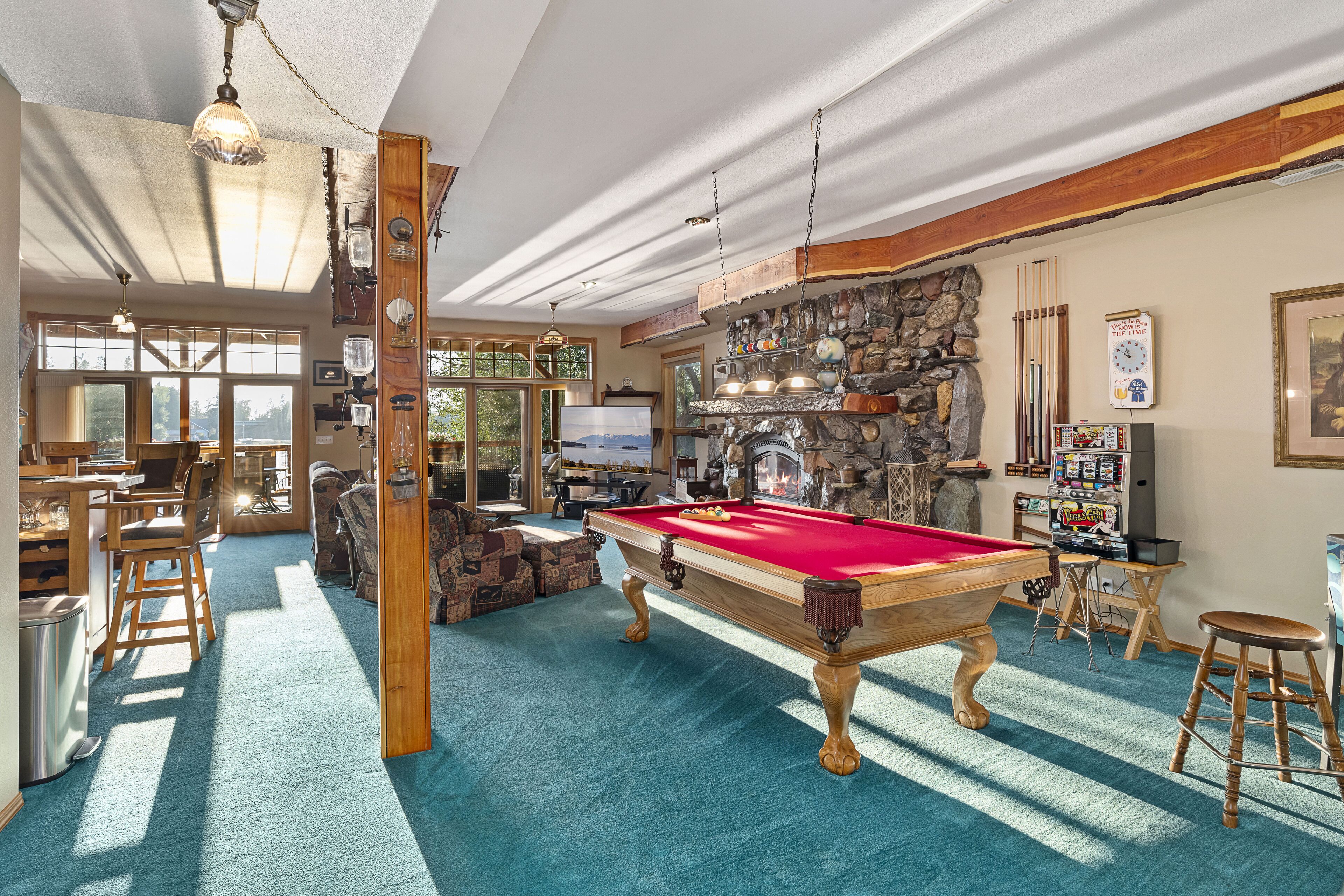 A pool table in a room with a stone wall, wooden beams, and a bar area.