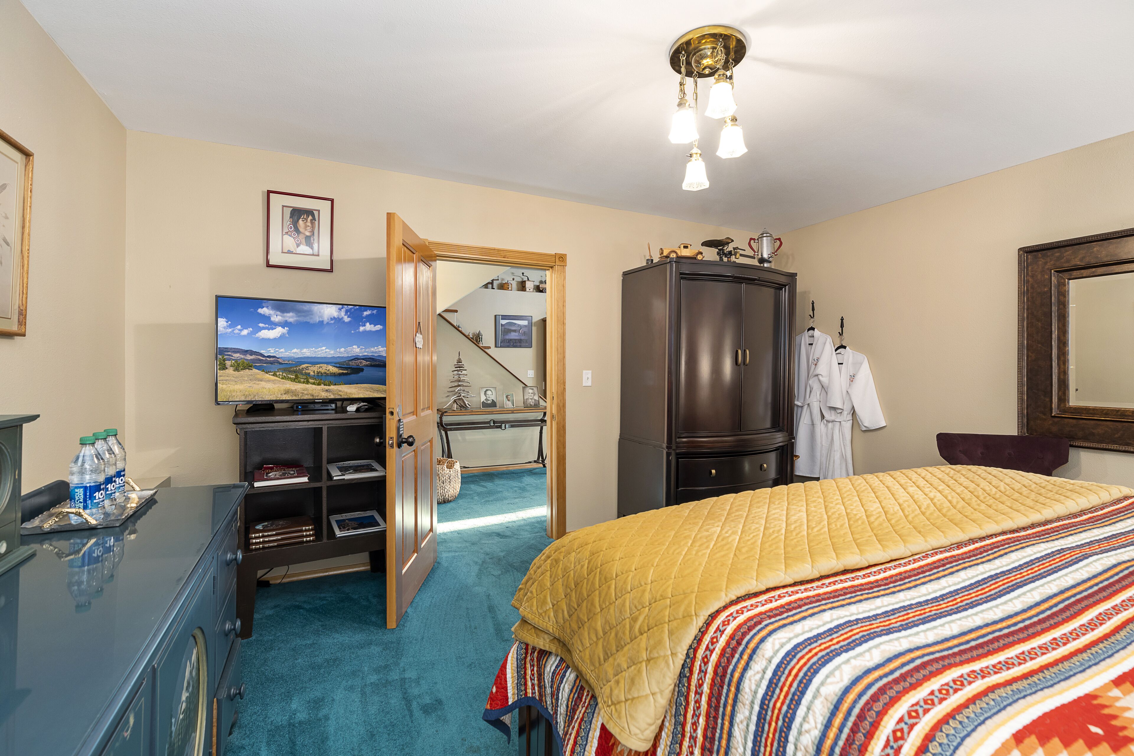A hotel room with a bed, a television, a wardrobe, and a desk with a computer.