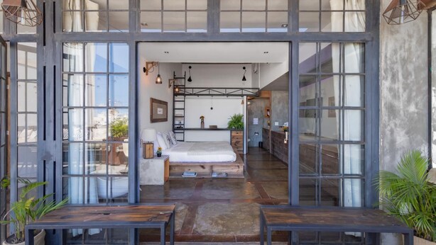 A modern bedroom with a large bed, a desk, and a view through floor-to-ceiling windows. - Ipanema Hills 7 Ensuites (Rio de Janeiro)