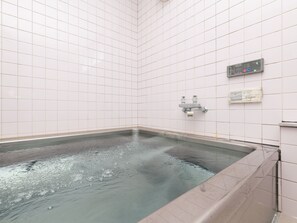 Un jacuzzi pequeño y rectangular con un panel de control en la pared.