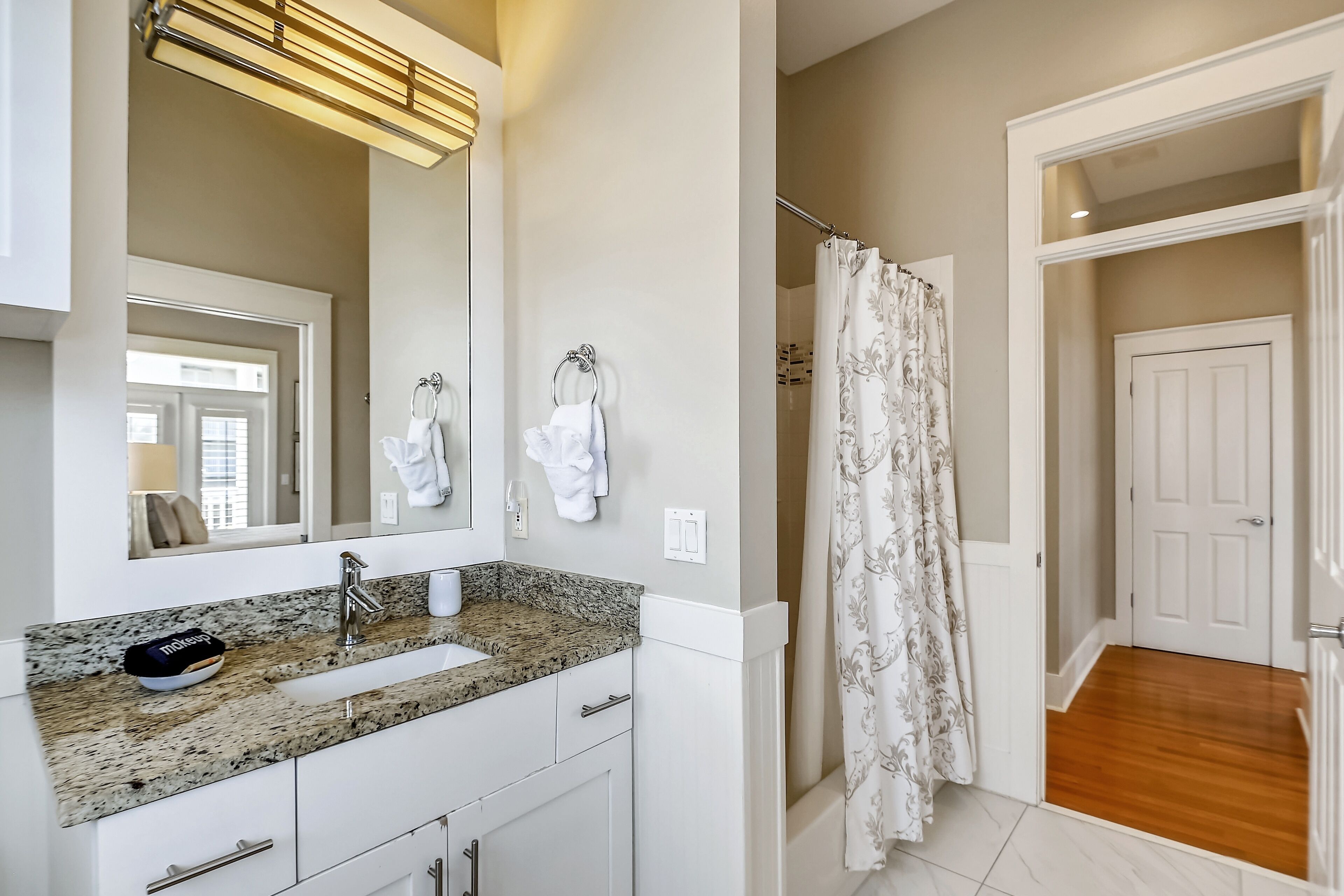 Une salle de bain avec un comptoir en granit, un lavabo, un miroir et une douche avec un rideau.
