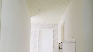 A hallway with wooden flooring, white walls, a white door, and a white cabinet. - Living in a country house near Bautzen/ OT Doberschau (up to 4 persons; vacation apartment) (Doberschau)