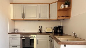 A compact kitchen with white cabinets, a built-in oven, a toaster, and a coffee maker. - Living in a country house near Bautzen/ OT Doberschau (up to 4 persons; vacation apartment) (Doberschau)