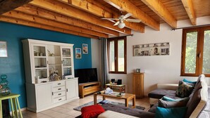 A living room with a wooden ceiling, a white entertainment unit, a sofa, and a television. - Gîte du Silence - Stylish gîte in beautiful French countryside (Coulx)