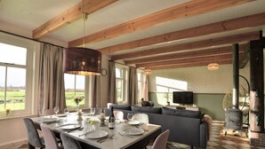 A dining area with a checkered floor, a dining table set for four, and a gray sofa in the background. - Stay at our beautiful farmhouse, enjoy the authentic atmosphere (Monnickendam)
