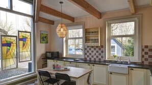A kitchen with a wooden ceiling, a large window, a sink, and a dining area with chairs. - Stay at our beautiful farmhouse, enjoy the authentic atmosphere (Monnickendam)