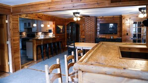 A wooden interior with a bar area, kitchen, and dining space. - Au Sable Riverview Resort (Grayling)