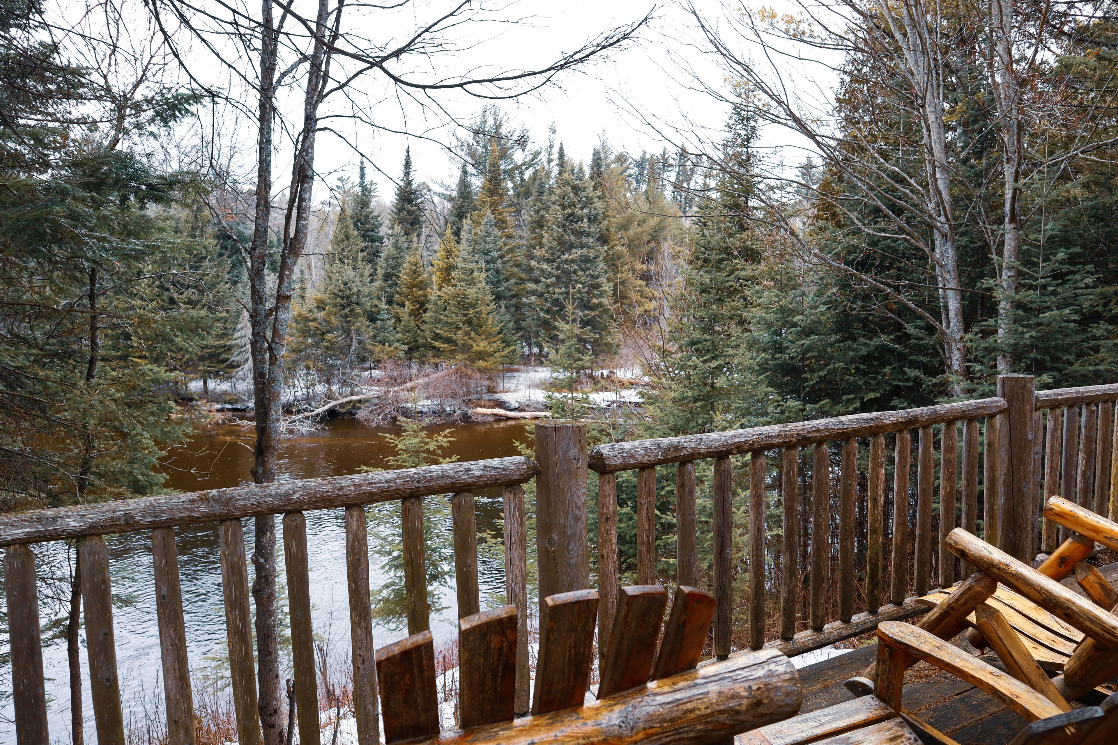 Una terraza de madera con vista a un río y un bosque.