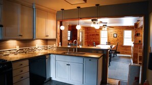 A modern kitchen with a central island, built-in appliances, and pendant lighting. - Au Sable Riverview Resort (Grayling)