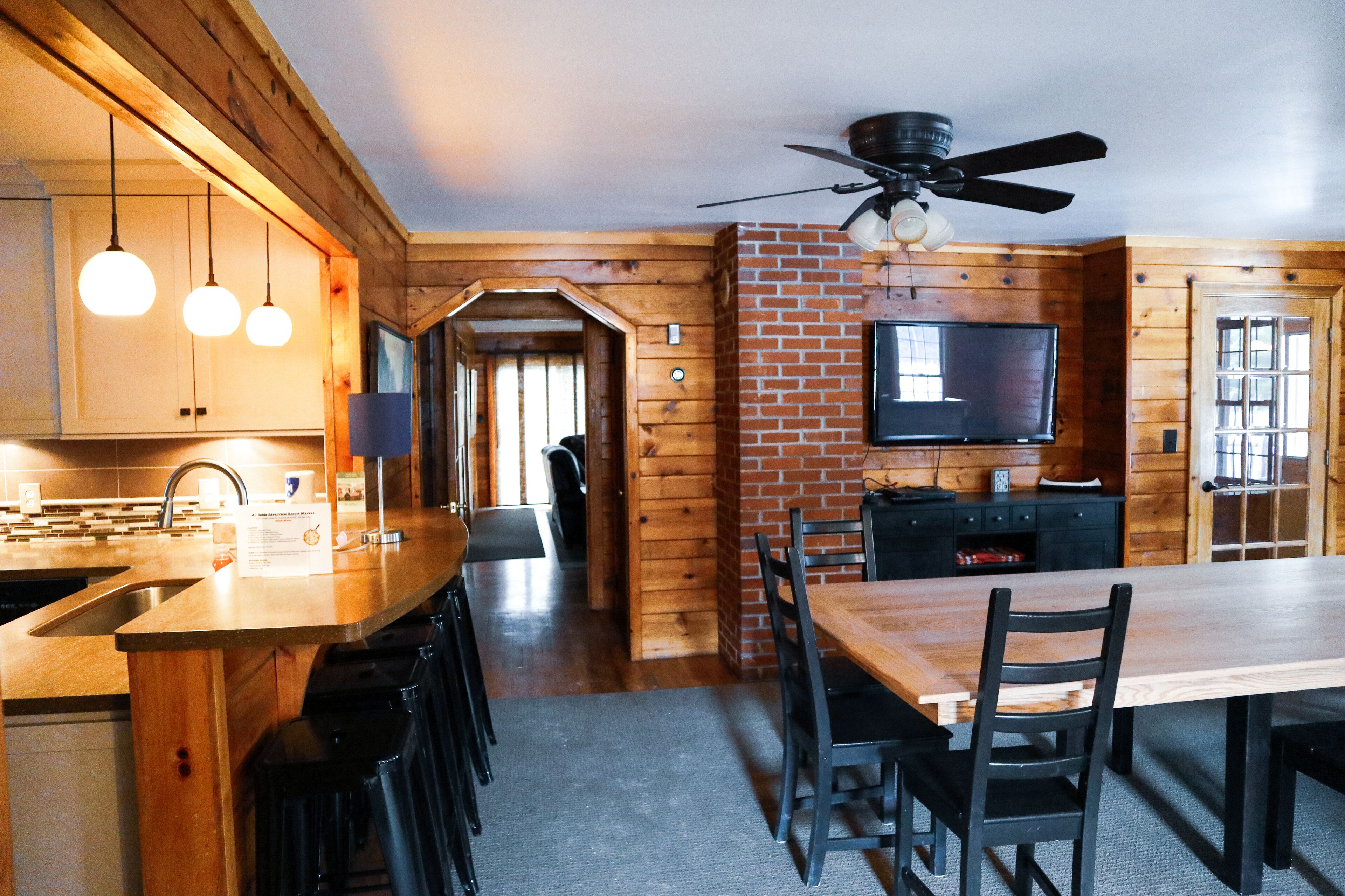 A wooden interior with a kitchen, dining area, and a TV mounted on the wall.