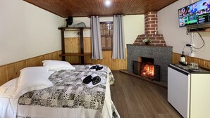 A cozy room with a bed, a fireplace, a television, and a small refrigerator. - Pousada Cruzeiro do Sul (Itatiaia)