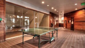 A ping pong table in a room with a tiled floor, wooden walls, and a glass partition. - Cozy Wildernest Retreat w/ Mountain Views + Pool & Hot Tub (Silverthorne)