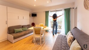 Een moderne woonkamer met een bank, een eettafel en een aan de muur bevestigde televisie.