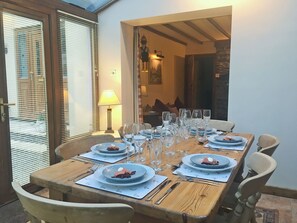 A dining table set with plates, glasses, and cutlery, with a lamp and a painting on the wall.