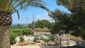A residential area with a paved driveway, a gated entrance, and a view of the sea.